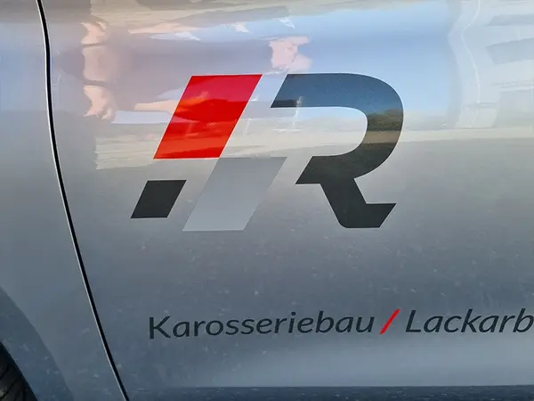 Firmenlogo und Schriftzug Karosseriebau Lackarbeiten auf silberner Autotür.